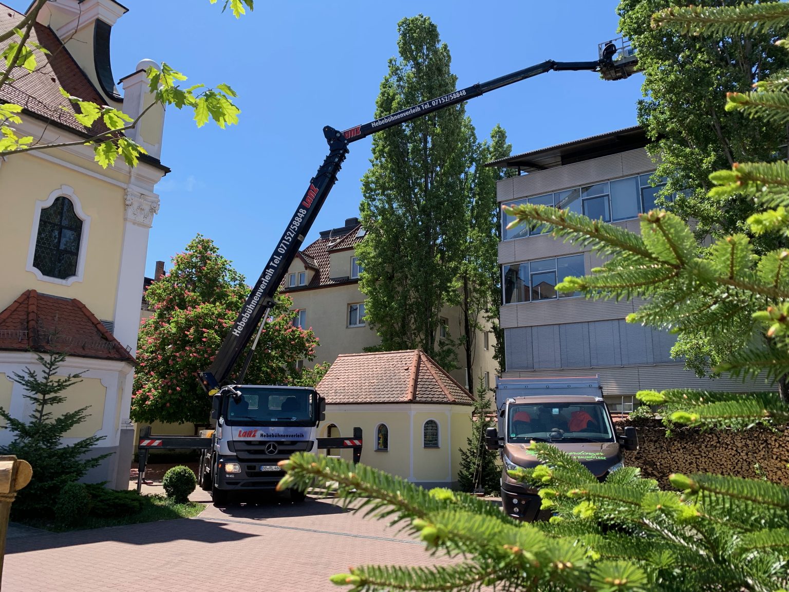 LKW-Arbeitsbühne bei Baumarbeiten neben einer Kirche